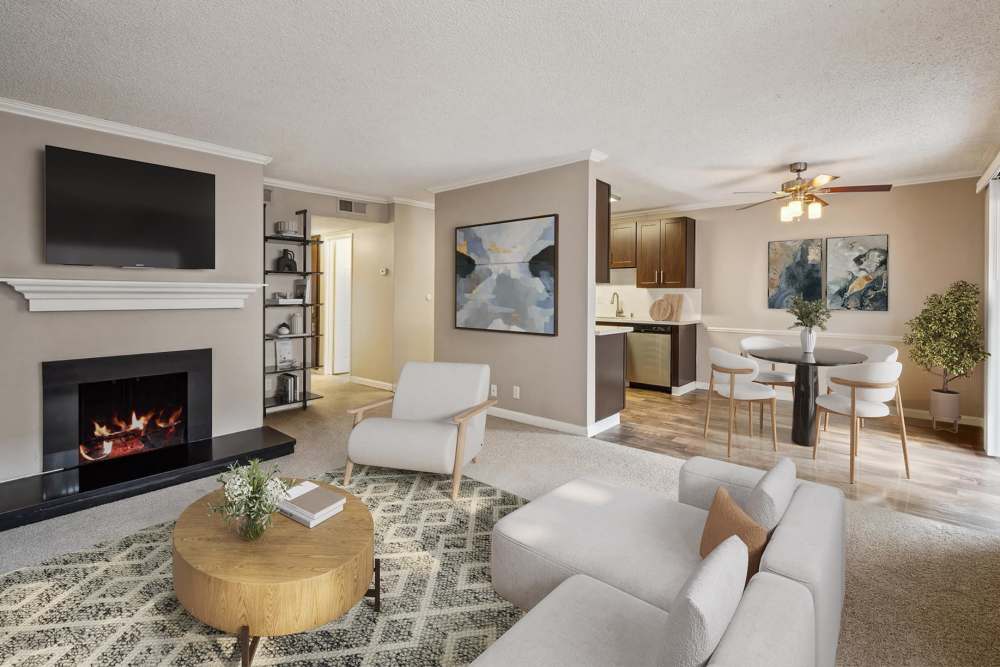 Spacious living room and kitchen with brown cabinets and white stone countertops at La Valencia Apartment Homes in Campbell, California