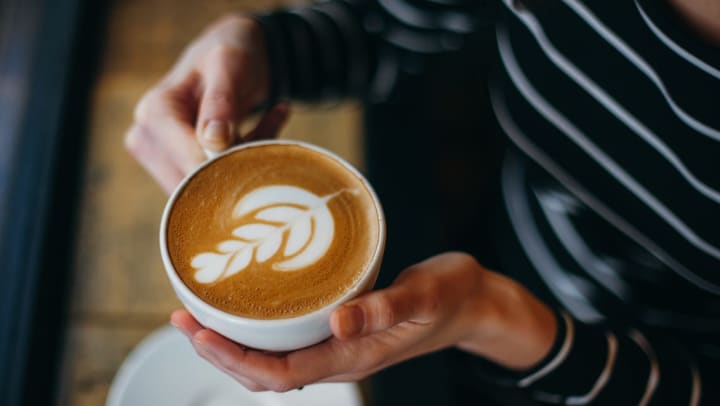 An aerial shot of a woman’s hands holding a latte | coffee shops in Katy