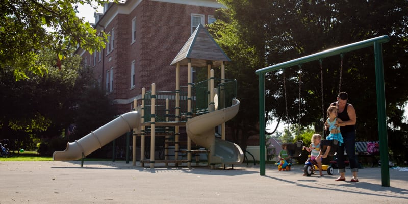 A resident and children playing at a playground at Perry Circle Apartments in Annapolis, Maryland