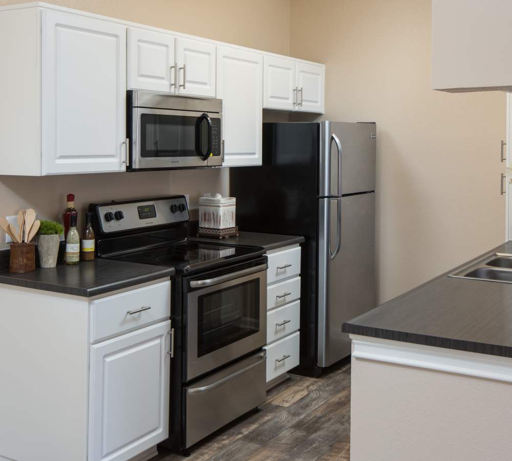 Kitchen with woodgrain countertops, white cabinets, and stainless steel appliances