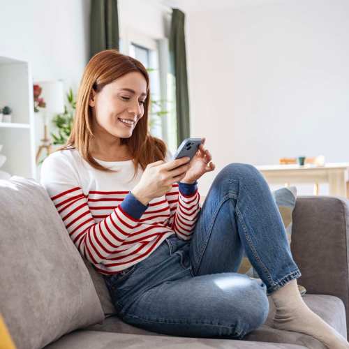 Resident woman using her phone in a living room at Truckee River Terrace in Reno, Nevada