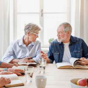 Residents sitting and reading a book as a group at The Spring at Silverton in Fort Worth, Texas