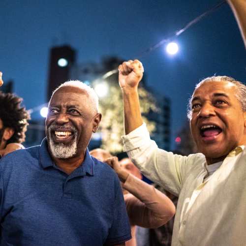 Two men smiling and raising fists in celebration near Avia Lofts at Maple Road in Amherst, New York