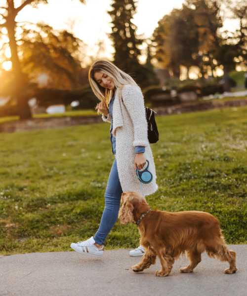 A resident strolling with her dog at a park near Penthouses at Capitol Park in Sacramento, California