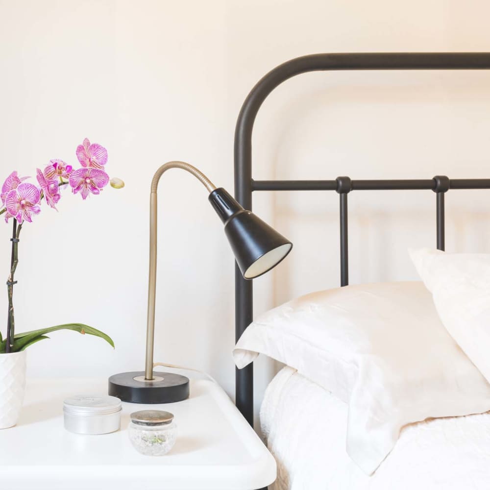 Close up of bed and a side table with lamp, flower plant at Sycamore Villas in Nashville, Tennessee