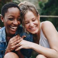 Best friends sharing a laugh on the stoep outside their apartment home at Sagebrush in Universal City, Texas