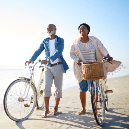 Resident couple walking their bikes on the beach near The Crossing at Palm Aire Apartment Homes in Sarasota, Florida