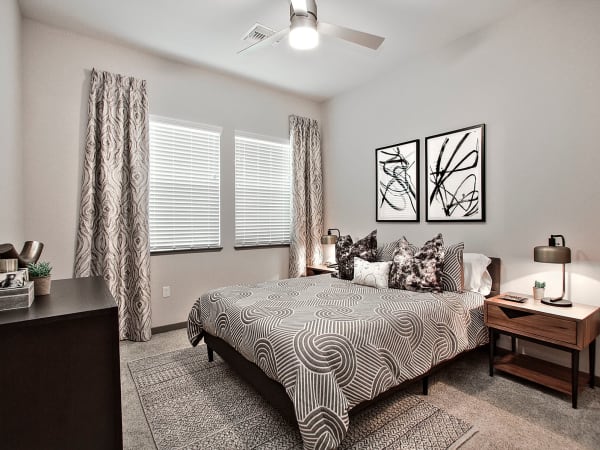 Beautifully decorated bedroom with a draped window and ceiling fan in a model home at Jade Apartments in Las Vegas, Nevada