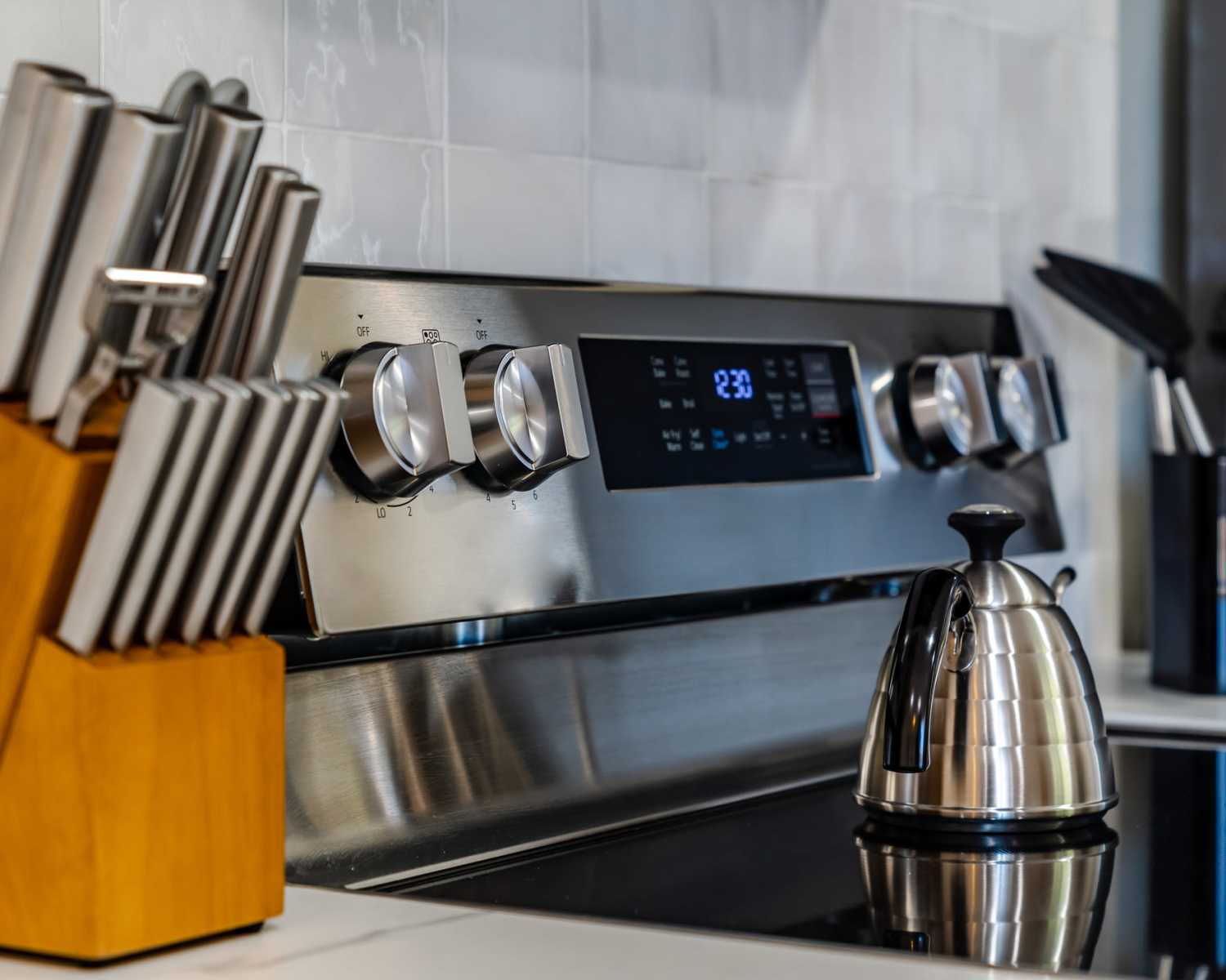 Stainless steel appliances with modern knobs and a sleek kettle on a glass cooktop at Harvest Hill in Broomfield, Colorado