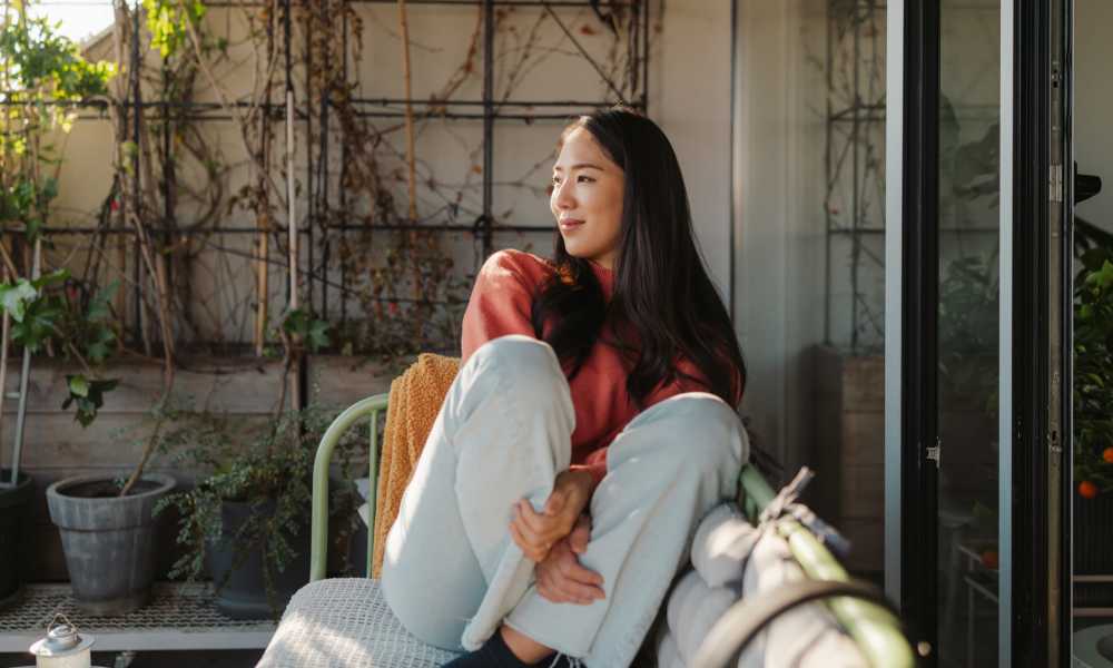 Happy resident sitting in chair in her apartment at Williston Pointe in Gainesville, Florida