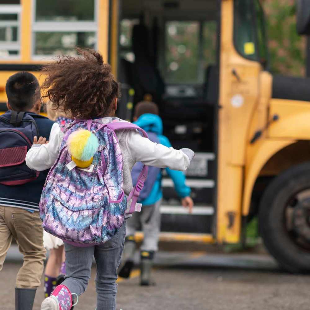 Resident children running cheerfully towards their school bus near Pine Bluff in Kingsford, Michigan