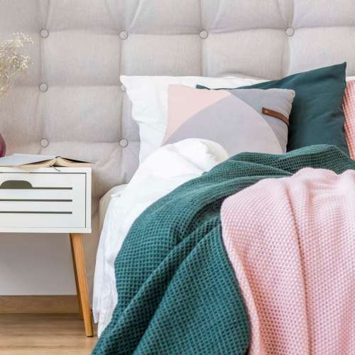 Bedroom with large comfortable bed and a side table at Antioch Family & Senior Apartments in Antioch, California