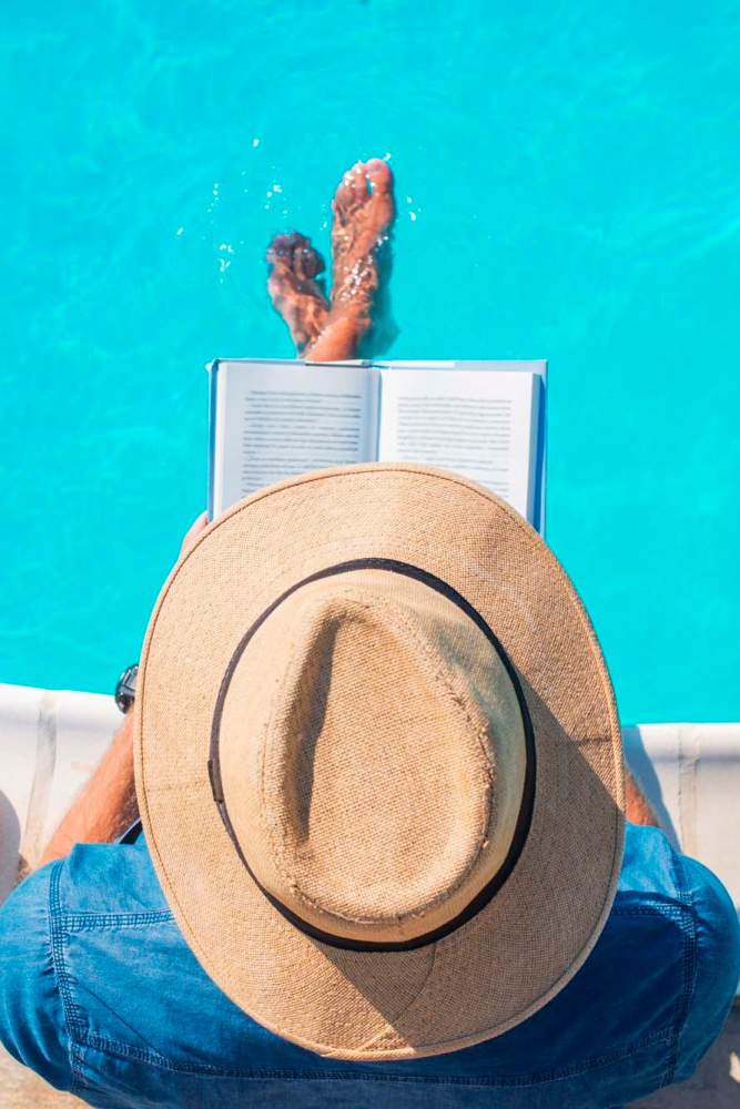 Resident reading a book by the community pool at Icon Apartments in San Antonio, Texas