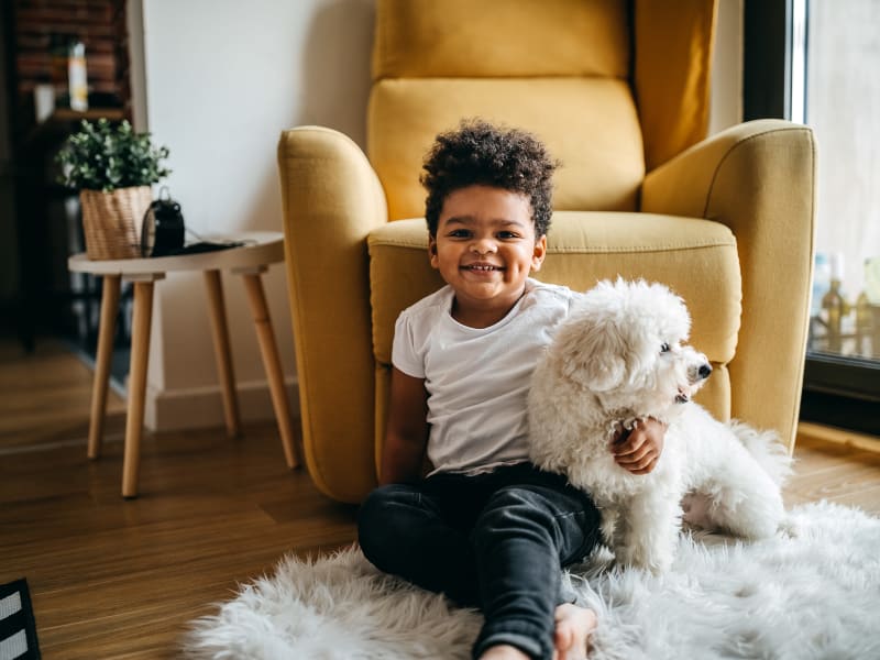 A young boy sitting on the floor with his dog at Hunt Club in Gaithersburg, Maryland