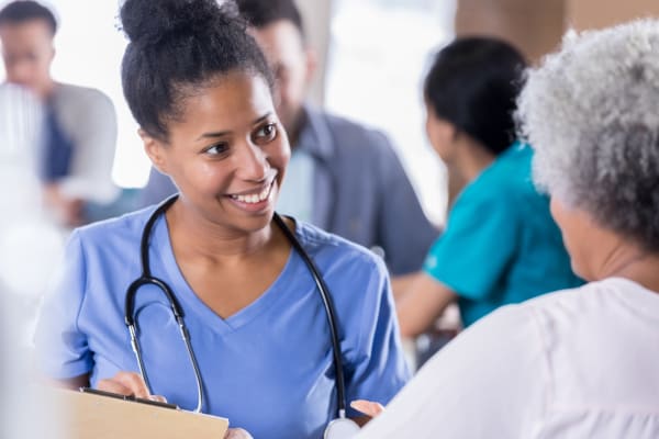 nurse in scrubs helping elderly patient