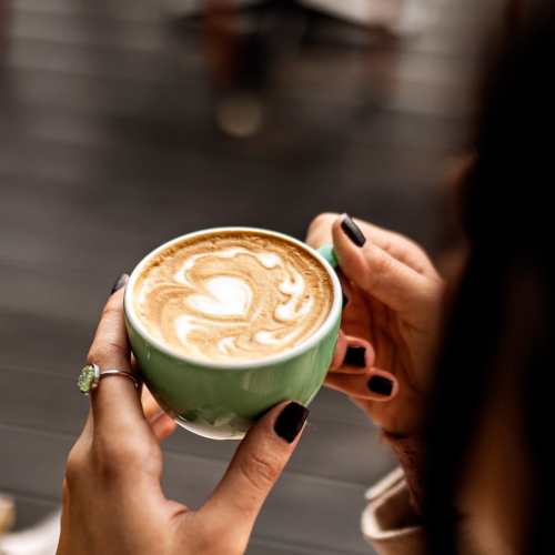 A woman holding a cup of coffee at a cafeteria near Wildwood Creek in Grapevine, Texas