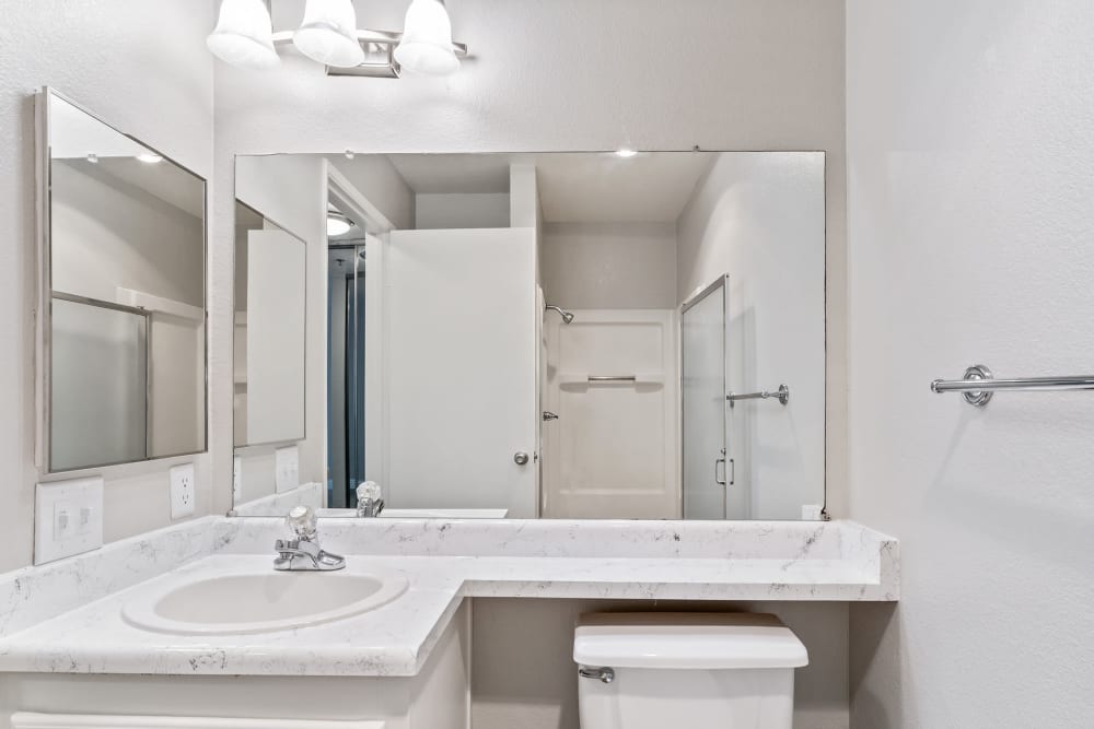 Bright white bathroom with standing shower at Quail Hill Apartment Homes in Castro Valley, California