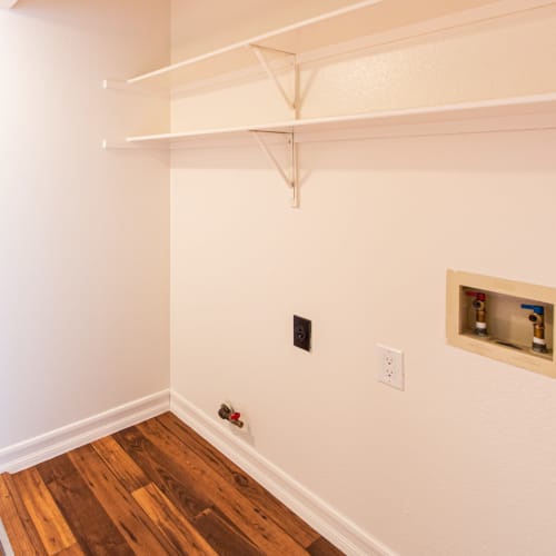 Storage shelves and washer and dryer hookups in a home at Howard Gilmore Terrace in La Mesa, California