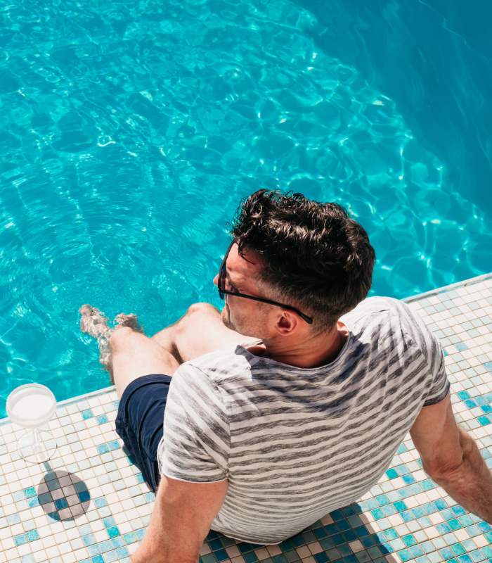 Man relaxing by a sparkling pool with water reflecting sunlight at ReNew Belcamp in Belcamp, Maryland