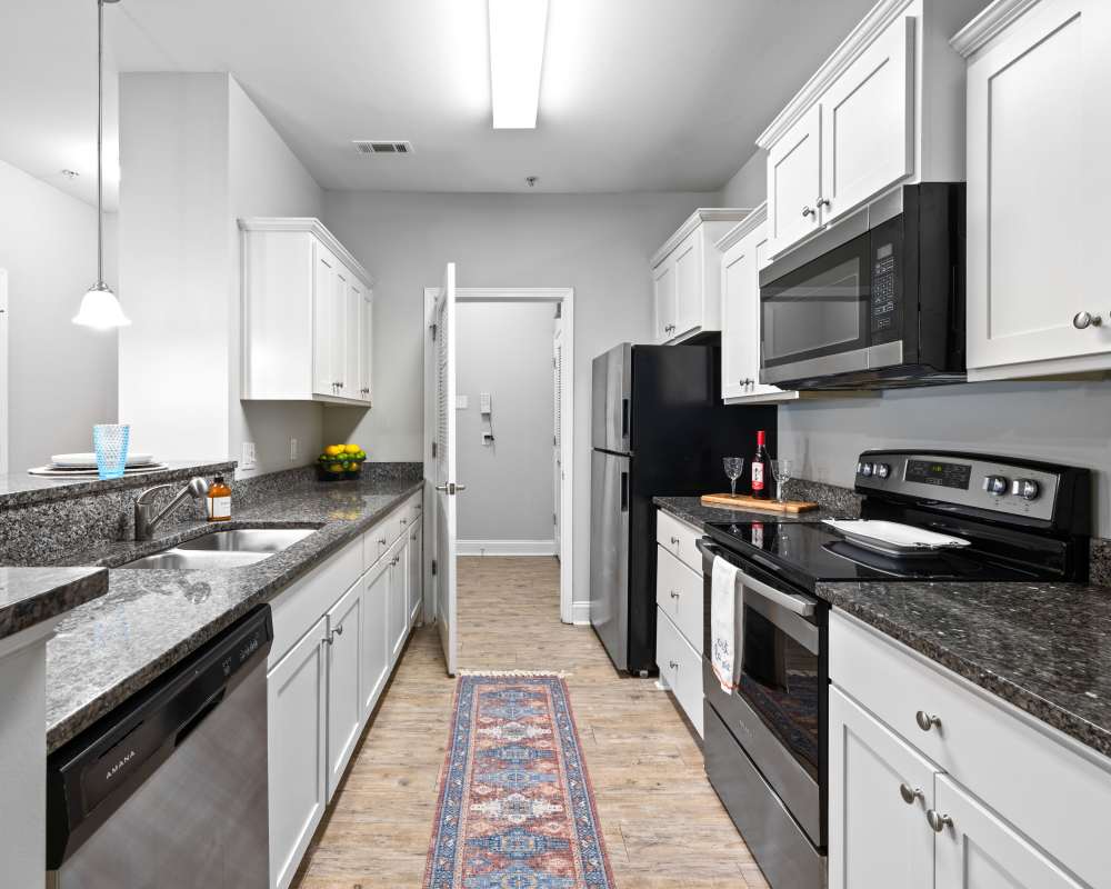 Large open-concept living area with hardwood floors and a ceiling fan in a model home at The Enclave in Brunswick, Georgia