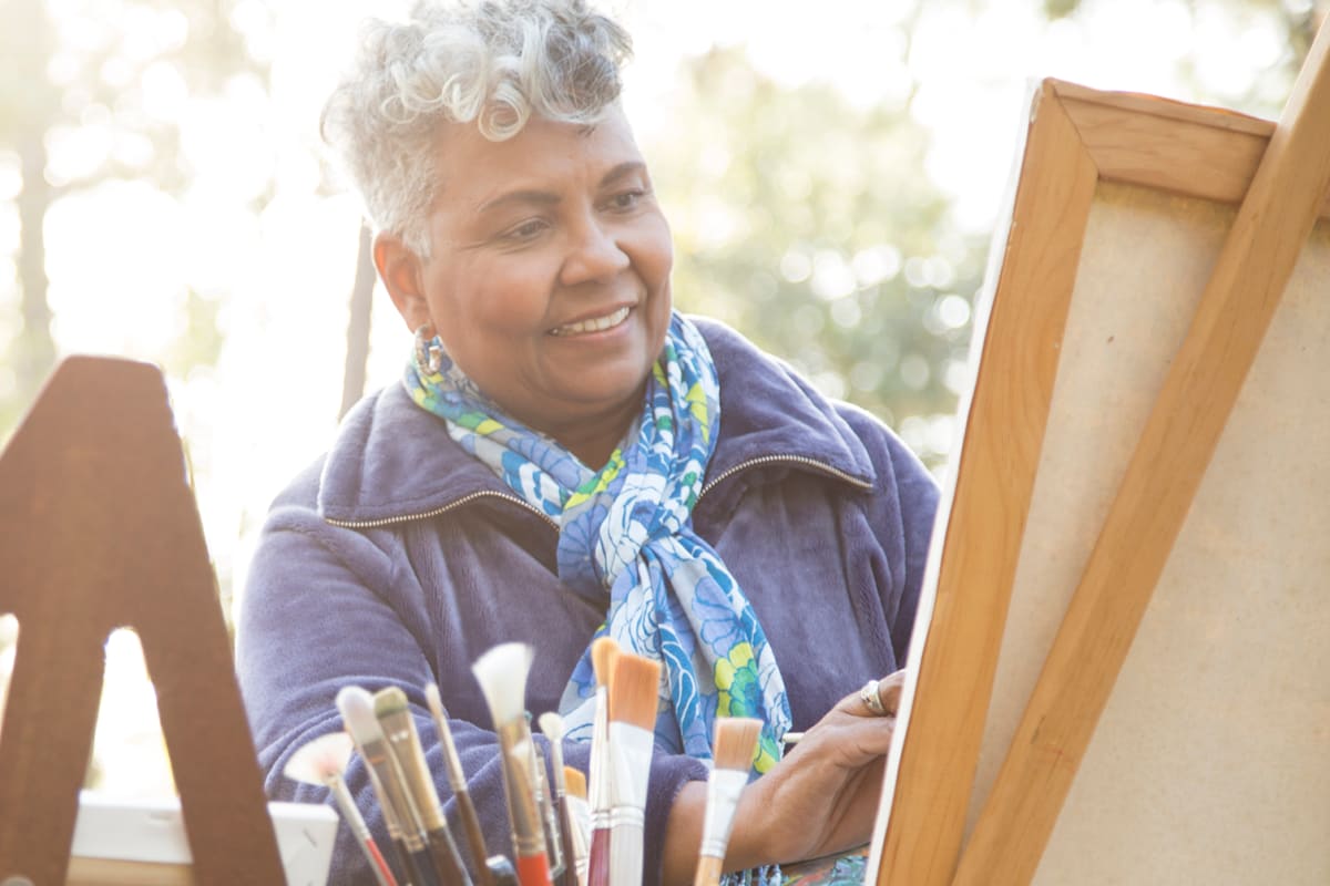 Resident painting a picture on an easel at Sierra Ridge Memory Care in Auburn, California