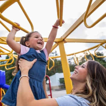 Mom helping daughter on the monkey bars at Whitman Villa Townhomes and Apartments in Hayward, California