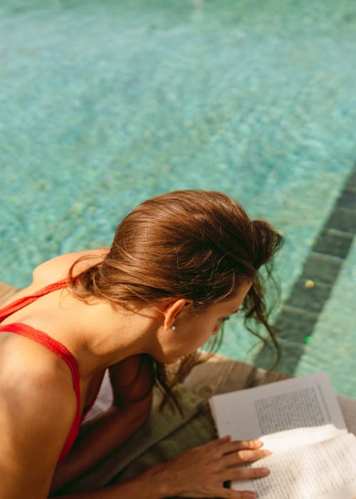 A resident reads a book poolside at University Lofts at Russellville, Russellville, Arkansas