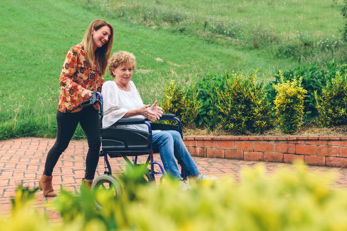 A resident in a wheel chair with a young woman assisting her at Victoria Park Personal Care Community in Regina, Saskatchewan