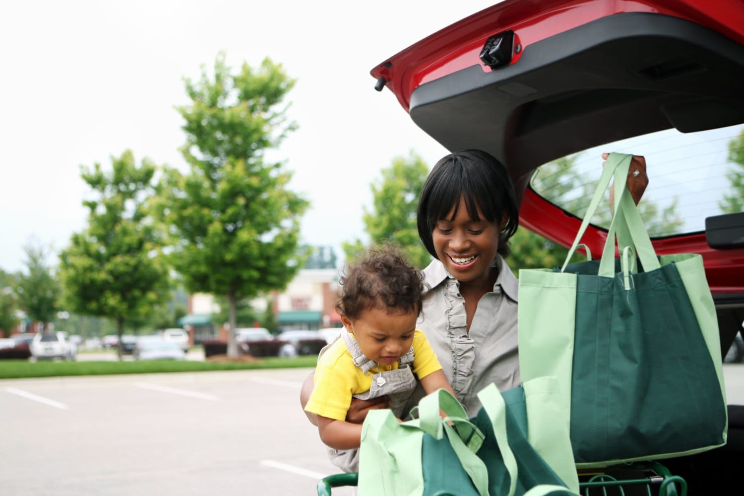 A mother holding a child and loading groceries into her car near Vista Villa in Charlotte, North Carolina