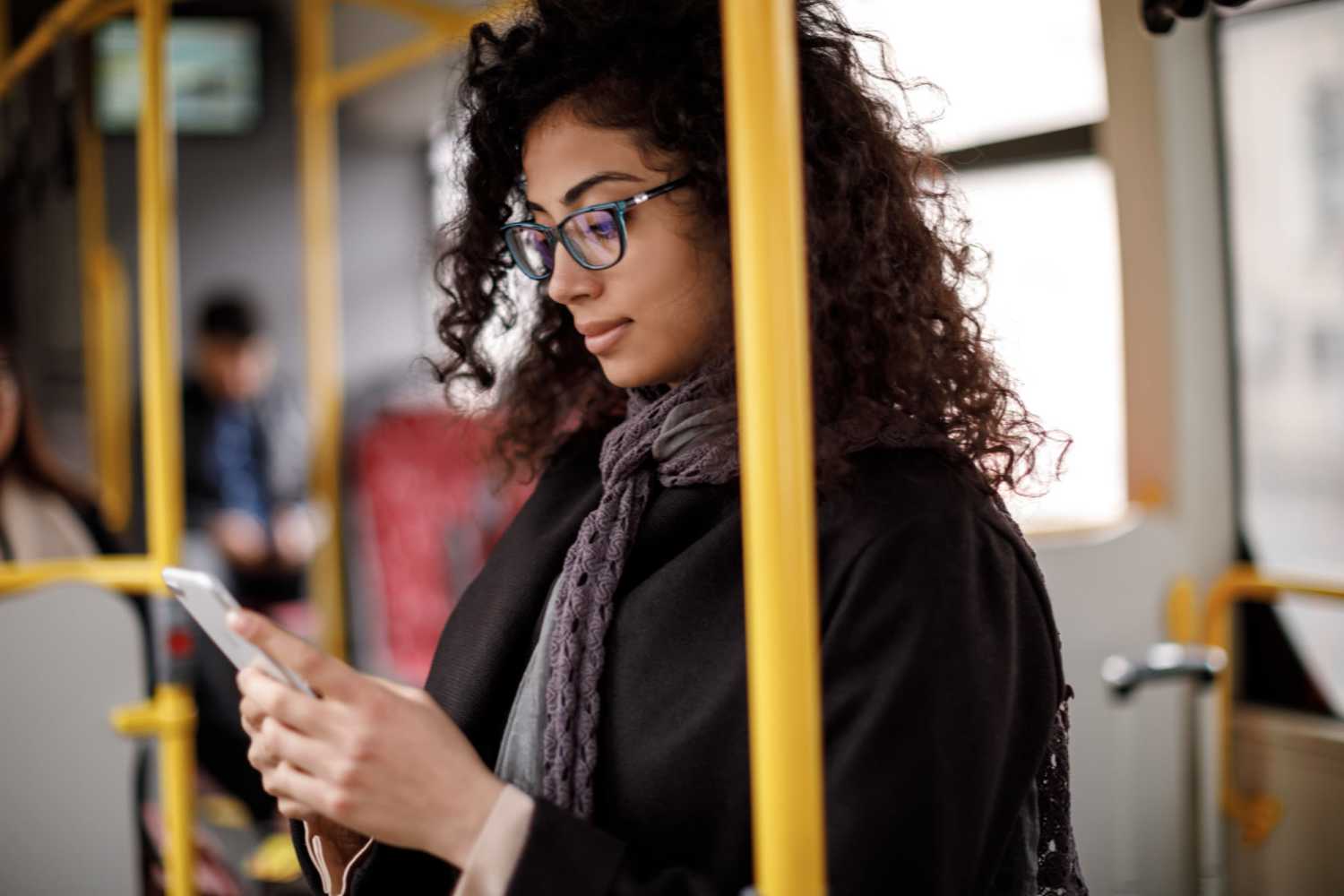  A woman wearing glasses and a scarf is focused on her phone at North Court Villas in Frisco, Texas