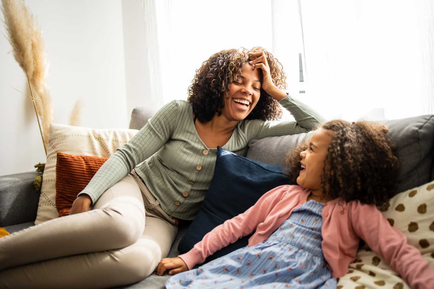 A mother and daughter are sitting together on a couch at Arlington Trace in Greenville, North Carolina