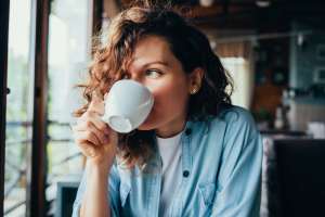 A woman holding a cup of coffee near Dogwood Terrace Apartments in Woodville, Texas