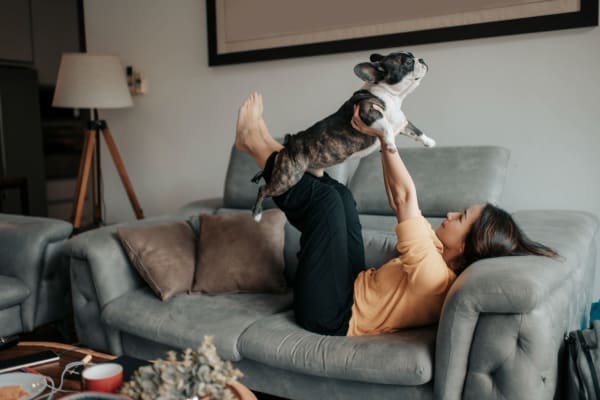 Resident holding their dog in the air in the living room of their new apartment at Parkside Towns in Richardson, Texas