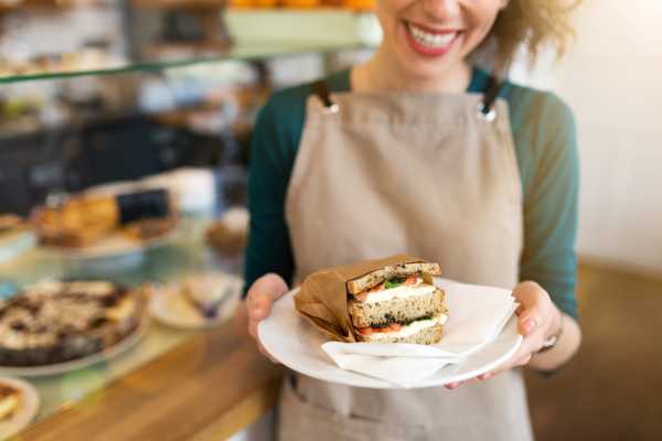 A woman holding a sandwich at a café near The Summit At Metrowest in Orlando, Florida