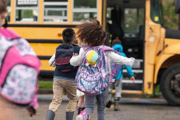 Children running towards school bus at Seagrove in Conroe, Texas