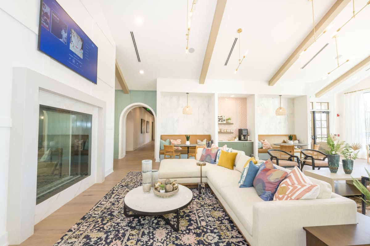 Indoor community area with large white sectional couch with television above the fireplace