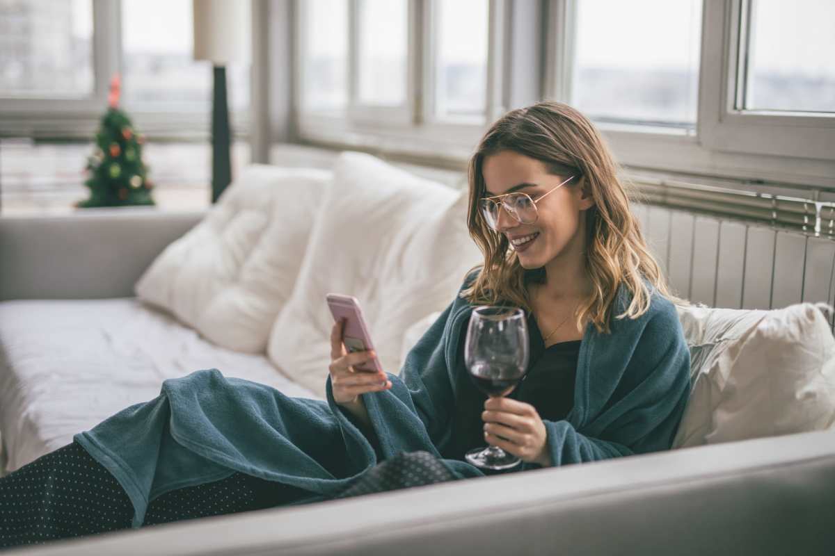 Woman using our online portal on her mobile while having wine at Woodlake Close in Sacramento, California