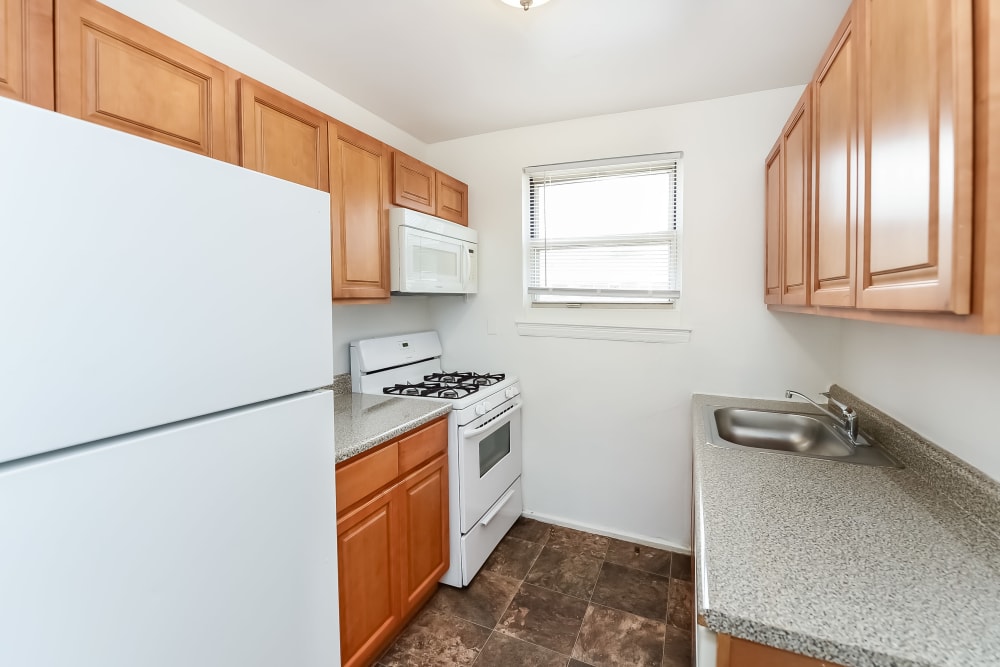 Fully-equipped kitchen with traditional maple cabinets at Elmwood Village Apartments & Townhomes in Elmwood Park, New Jersey