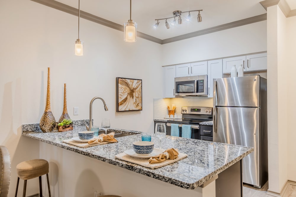 Upscale kitchen with granite counters and modern lighting at Haven at Lewisville Lake in Lewisville, Texas.