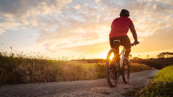 A biker in a red shirt cycling away from the camera at dawn | Bike Trails Near Chandler