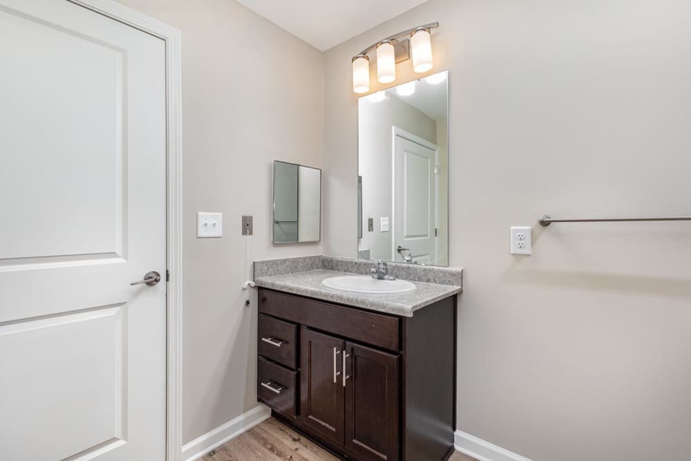 Modern bathroom with granite countertops, dark wood cabinetry, and wood-style flooring at Galloway Crossing in Charlotte, North Carolina