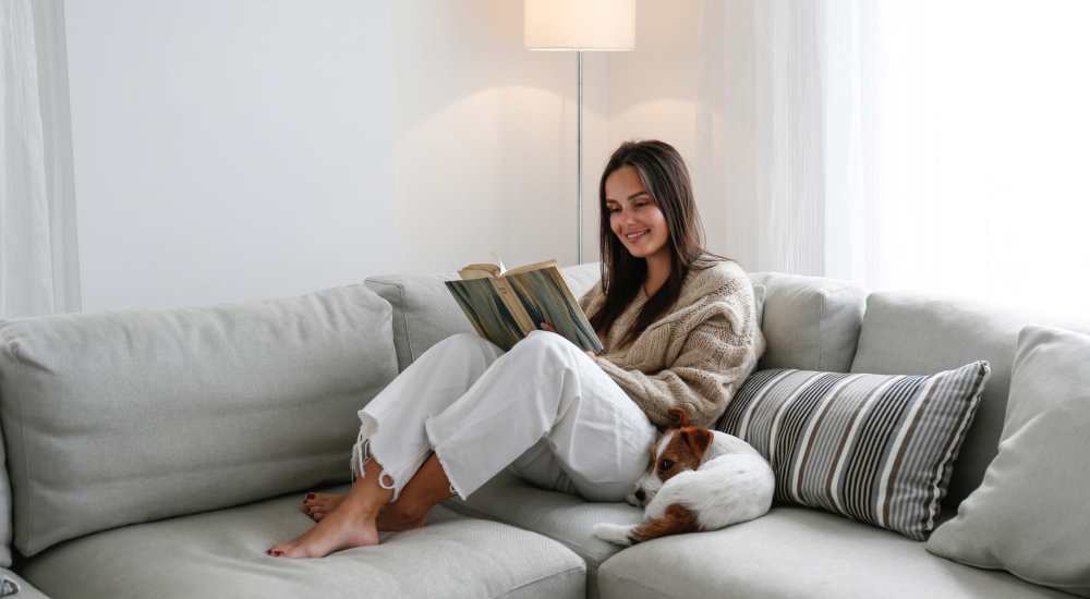Resident reading book in her living room with her dog at Reseda On The Park in Reseda, California