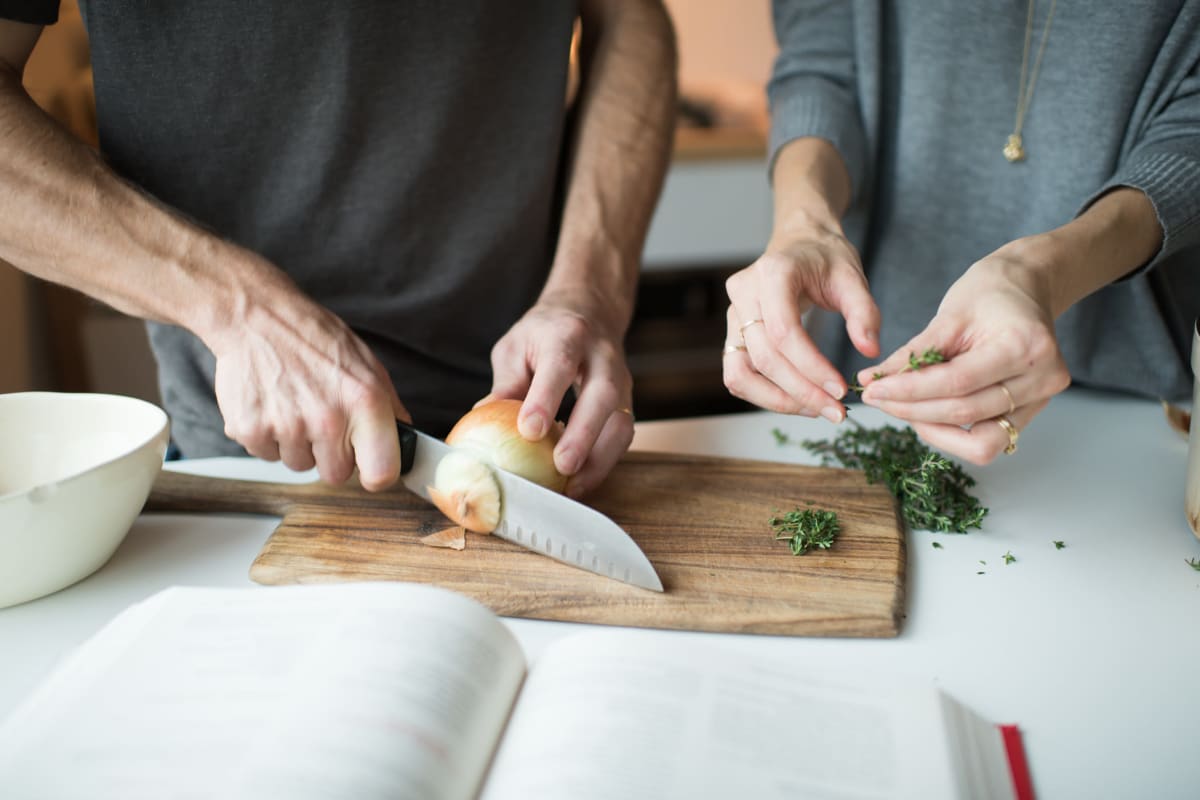 Residents cutting and preparing food in their well-equipped kitchen at Amira Roseville in Roseville, Minnesota