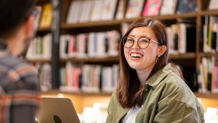 two people sitting at a table with books and laptop computer | library in Katy