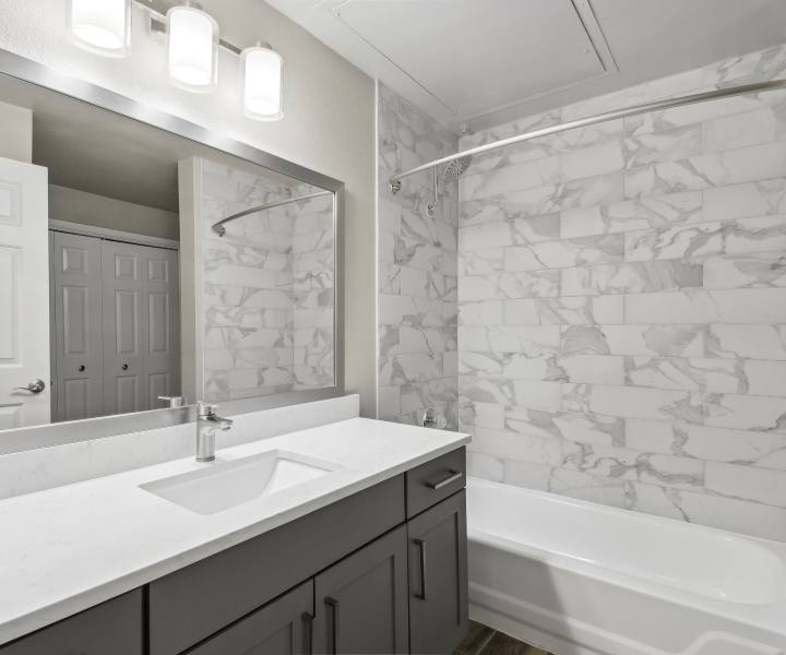 Modern bathroom with vanity light, mirror, sink and standard bathtub at Charleston in San Antonio,Texas