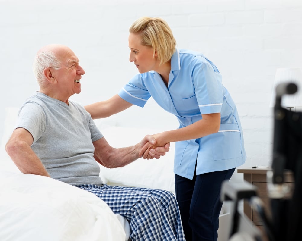 Staff helps resident out of bed at Willows Landing in Monticello, Minnesota.