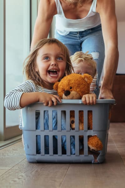 Child riding in a laundry basket at home at Reserve at South Coast in Santa Ana, California