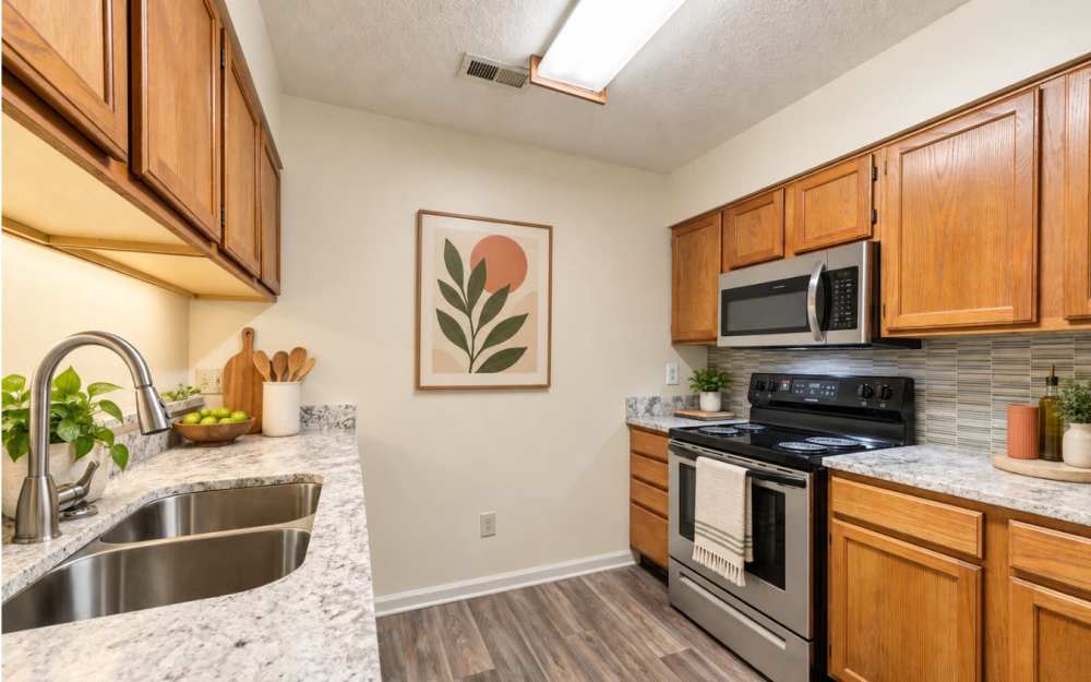 Kitchen with wood cabinets, quartz-style counters and stainless sink at Chason Ridge Apartment Homes in Fayetteville, North Carolina 