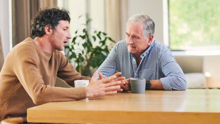 Senior and adult son talking at a table 