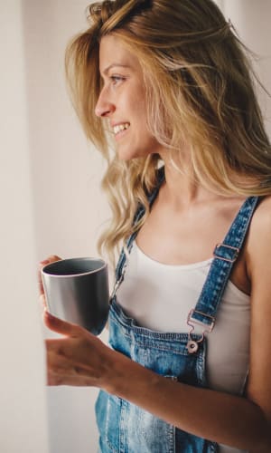 Resident looking out her window while she savors her morning coffee at The Majestic at Hewitt in Hewitt, Texas